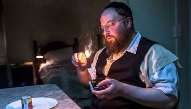 Menashe Lustig lights a memorial candle for his deceased wife
