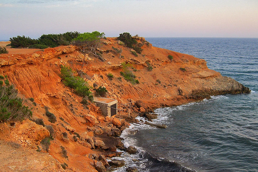 fisherman’s shacks below red cliffs on the water’s edge