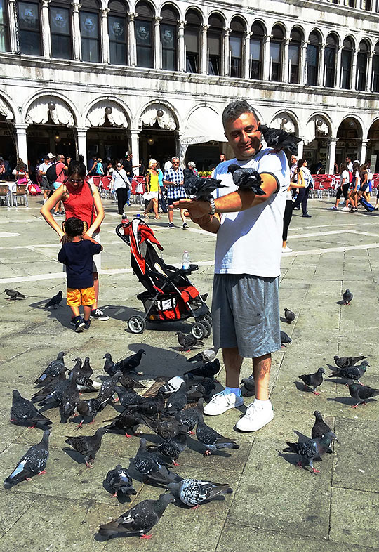 man feeding pigeons at the Piazza San Marco