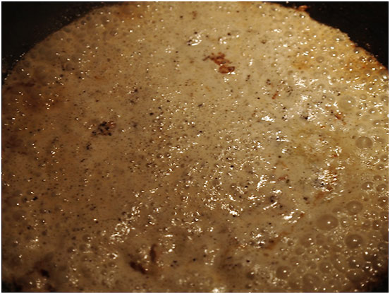 mixture of heaavy cream, plum brandy, ground black pepper, olive oil and butter cooking in skillet