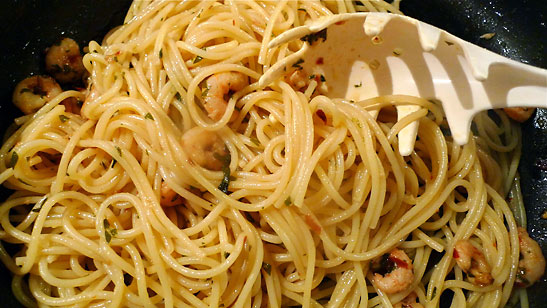 cooked spaghetti noodles added to olive oil, garlic and red pepper mix in skillet